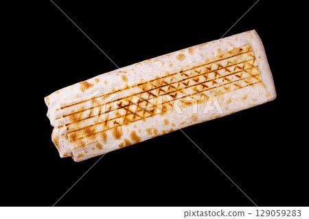 Warm shawarma flatbread with grill marks rests against a dark background 129059283