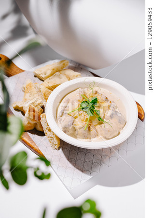 Tasty dip served with crispy bread on a wooden plate 129059433