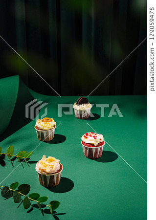 Delicious cupcakes arranged beautifully on a green surface with leaves 129059478