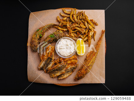 Delicious assortment of fried fish and sides served with dipping sauce Delicious assortment of fried fish and sides served with dipping sauce 129059488