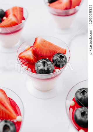 Colorful dessert cups with strawberries and blueberries on a white surface Colorful dessert cups with strawberries and blueberries on a white surface 129059522