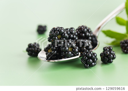 Ripe juicy blackberries on a green background 129059616