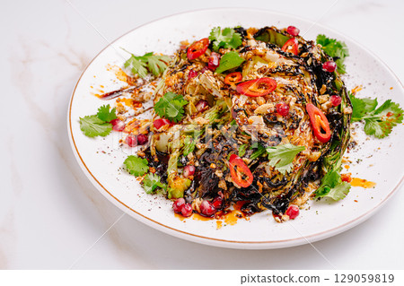 Grilled cabbage salad with pomegranate and cilantro served on white plate Grilled cabbage salad with pomegranate and cilantro served on white plate 129059819