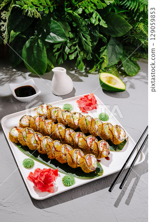 Sushi rolls served on a decorative plate with garnishes and sauces Sushi rolls served on a decorative plate with garnishes and sauces 129059853