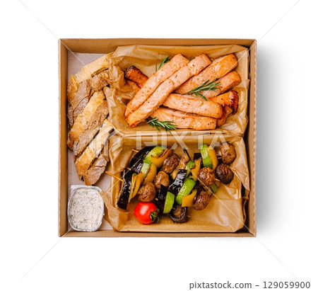 Delicious grilled salmon and vegetable platter served in a takeout box Delicious grilled salmon and vegetable platter served in a takeout box 129059900