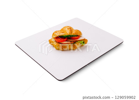 Delicious croissant sandwich with fresh ingredients on a white surface 129059902
