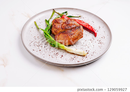 Grilled meat with scallions and chili peppers on elegant plate 129059927