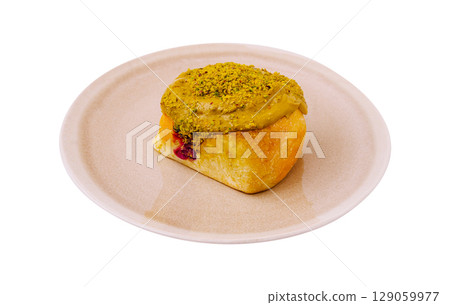 Delicious pastry topped with creamy spread and crushed nuts on a plate 129059977