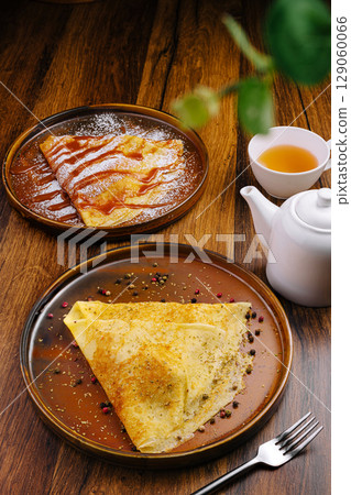 Delicious crepes served on wooden table with tea 129060066