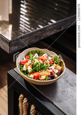 Delicious mixed green salad with shrimp and fresh vegetables on a modern table 129060076