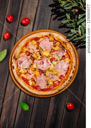 Delicious pizza topped with ham, chicken meat, and cherry tomatoes on wooden table 129060077