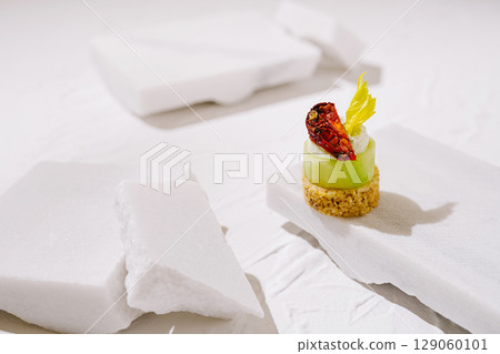 Delicate green appetizer served on minimalist white slate with garnishes 129060101