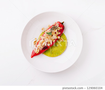 Delicious stuffed chili pepper served on a green sauce with toppings Delicious stuffed chili pepper served on a green sauce with toppings 129060104