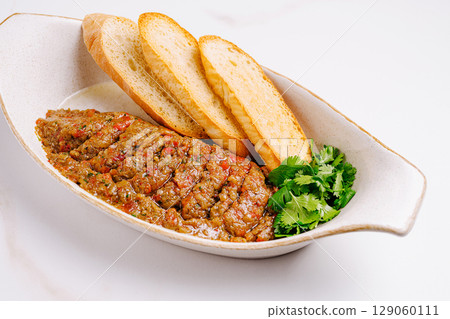 Eggplant spread served with toasted bread slices and fresh cilantro 129060111