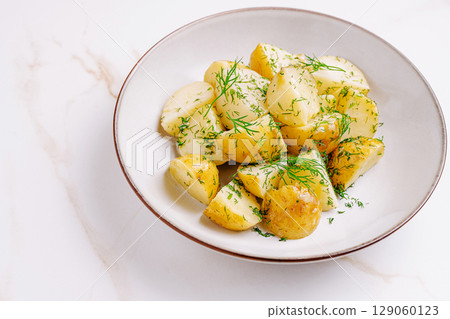 Freshly prepared boiled potatoes garnished with dill served in a bowl 129060123