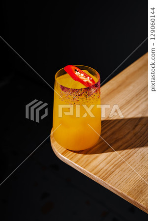 Refreshing cocktail with a spicy twist served on a wooden table 129060144