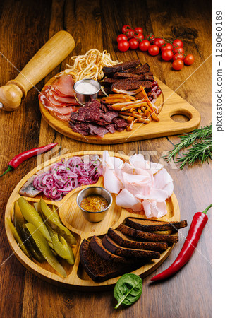 Charcuterie board with assorted meats and vegetables on wooden table Charcuterie board with assorted meats and vegetables on wooden table 129060189