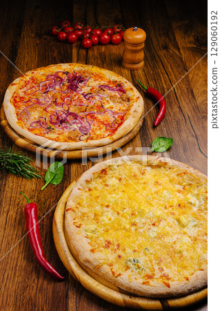 Delicious pizzas topped with cheese and vegetables on wooden table 129060192