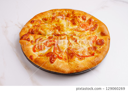 Freshly baked pizza with melted cheese and sliced tomatoes on display 129060269
