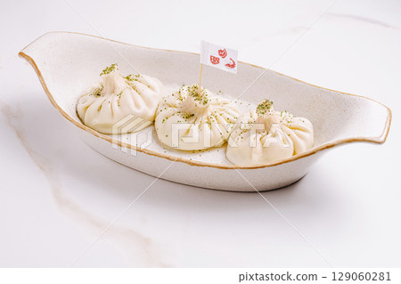 Delicious handmade khinkali served in a white dish with decorative flag 129060281