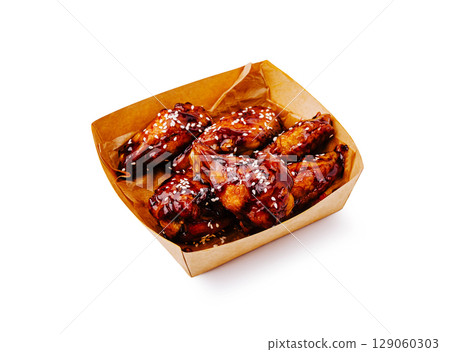 Crispy chicken wings with sweet glaze served in a takeaway box 129060303