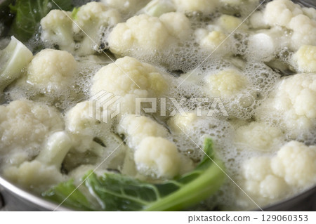 Fresh cauliflower is boiled in a saucepan with water. The vegetable is divided into florets and boiled in a saucepan. Fresh cauliflower is boiled in a saucepan with water. The vegetable is divided into florets and boiled in a saucepan. 129060353