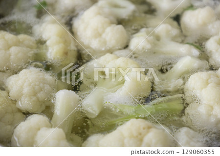Fresh cauliflower is boiled in a saucepan with water. The vegetable is divided into florets and boiled in a saucepan. 129060355