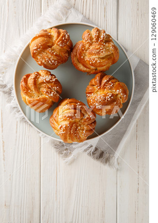 Sticky Braided sweet Knots with pearl sugar closeup on the plate. Vertical top view 129060469