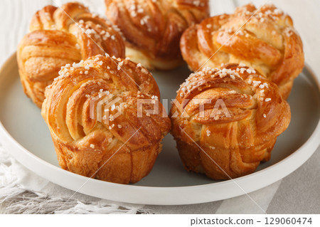 Knot sweet vanilla buns with pearl sugar close-up in plate. horizontal Knot sweet vanilla buns with pearl sugar close-up in plate. horizontal 129060474