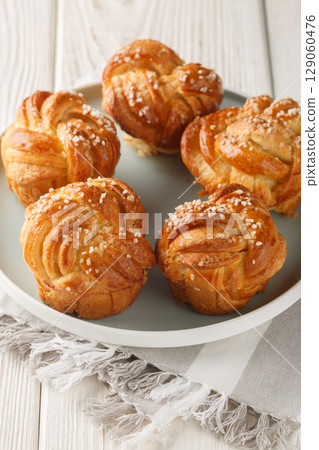 Knot sweet vanilla muffins with pearl sugar and vanilla close-up in a plate. Vertical 129060476