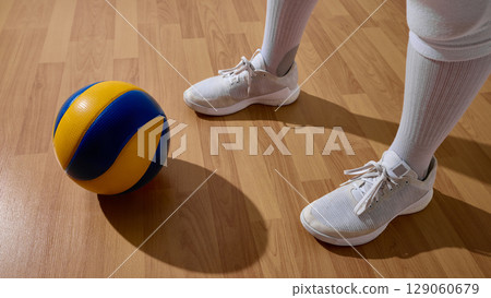 Athlete holding volleyball on indoor wooden court highlighting sportsmanship 129060679