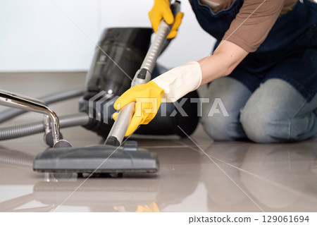 Floor Cleaning. Person vacuuming tiled floor with vacuum cleaner. Floor Cleaning. Person vacuuming tiled floor with vacuum cleaner. 129061694