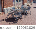 Outdoor metal tables and chairs on a sunny sidewalk cafe patio. 129061829