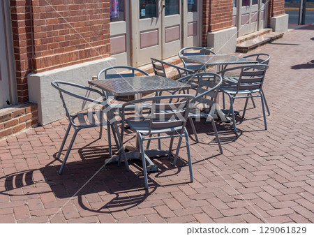 Outdoor metal tables and chairs on a sunny sidewalk cafe patio. 129061829