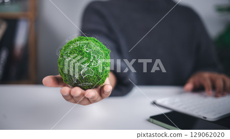 Environmental protection is symbolized by a moss covered green globe with a translucent world map held in hand, representing sustainability, ecological care, and global conservation efforts. 129062020