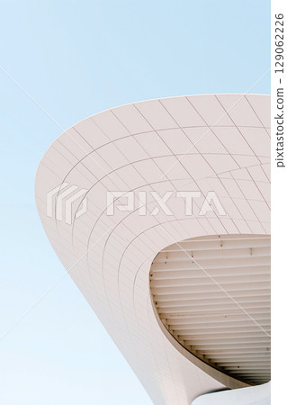 Modern Architectural Design With a Sleek, Curved Roof Against a Clear Sky 129062226