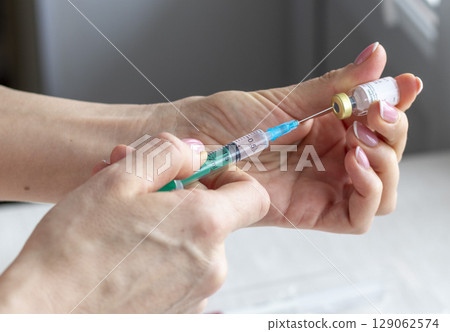 Close upshot of the woman preparing medicine for injection. 129062574