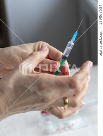 Close upshot of the woman preparing medicine for injection. Close upshot of the woman preparing medicine for injection. 129062584