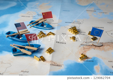 Miniature boats featuring USA, China, Turkey flags and gold bars arranged on a world map, symbolizing global geopolitical dynamics and economic trade relations 129062704