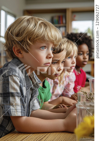 Group of children engaged in learning activity, focused on classroom project with materials 129062727
