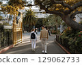 Students walking together through a school garden pathway surrounded by lush greenery and trees 129062733