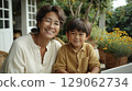 Smiling woman and young boy enjoying time together in a cozy garden setting with flowers 129062734