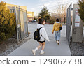 Two young women walking through school gates, ready for back to school season with backpacks 129062738