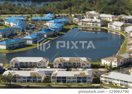 Residential condos with leaking roofs covered with protective tarp sheets against rain water leaks until replacement of shingles. Damage of building rooftops as aftermath of hurricane in Florida 129062790