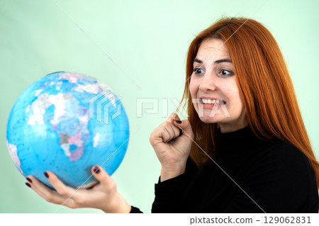 Portrait of a sad worried young woman holding geographic globe of the world in her hands. Travel destination and planet protection concept. 129062831