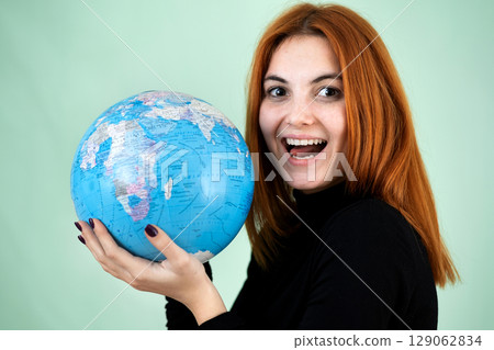Portrait of a happy young woman holding geographic globe of the world in her hands. Travel destination and planet protection concept. 129062834