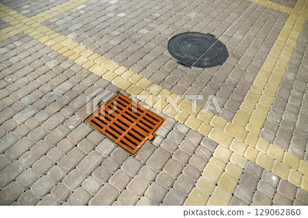 Old rusted metal gutter for rain water on the stone paved sidewalk. 129062860