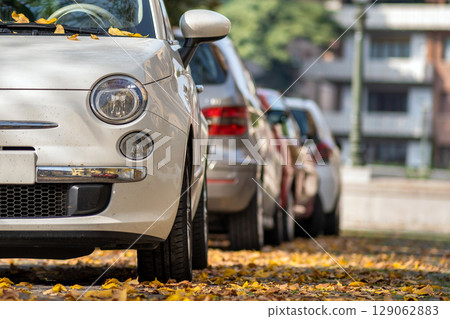 Modern cars parked on city street side in residential discrict. Shiny vehicles parked by the curb. Urban transportation infrastructure concept. 129062883