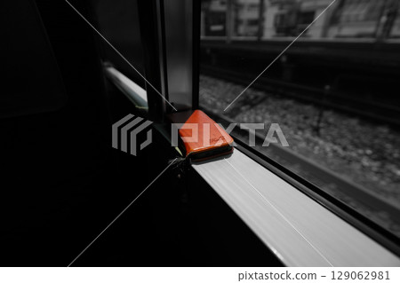 A red smartphone case placed by the train window 129062981