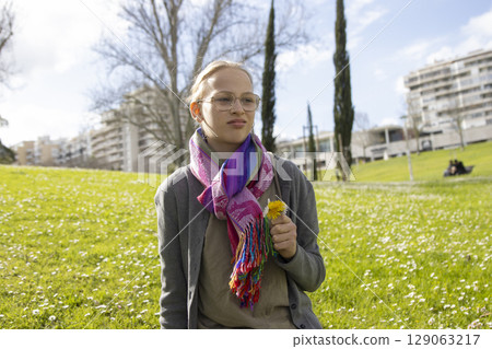Young woman holding dandelion in urban park during springtime Young woman holding dandelion in urban park during springtime 129063217
